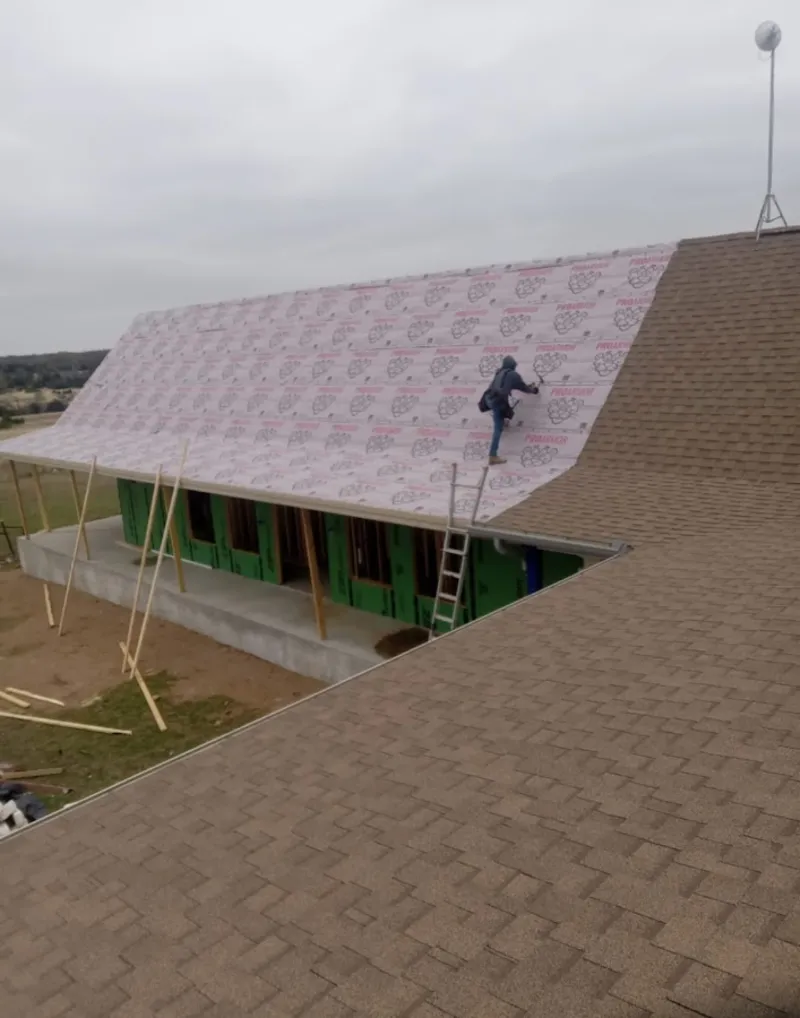 Worker preparing underlayment for a metal roof installation in Spring Hill